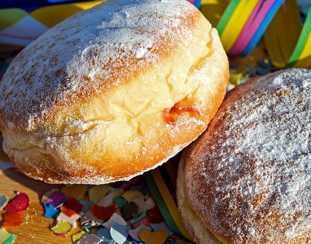 Zwei mit Puderzucker bestreute Krapfen auf einem Tisch mit Luftschlangen